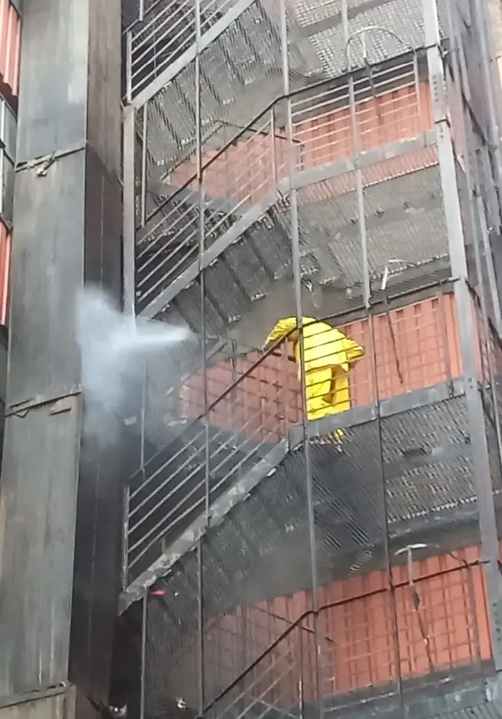 Worker carrying out surface cleaning on the external steel staircase