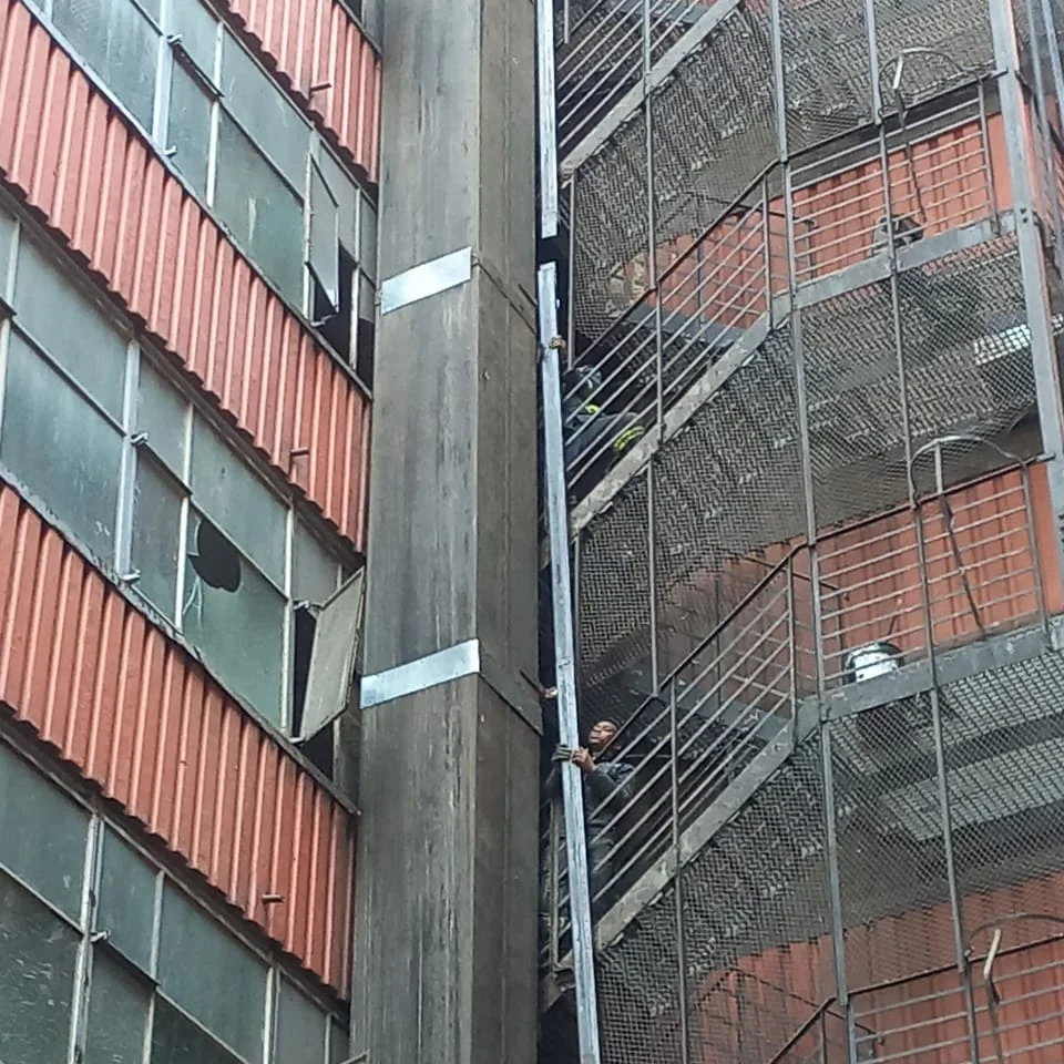 Workers handling steelwork beside the external fire escape